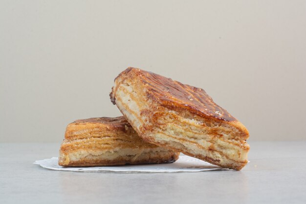 Two fresh delicious pastry on white table.