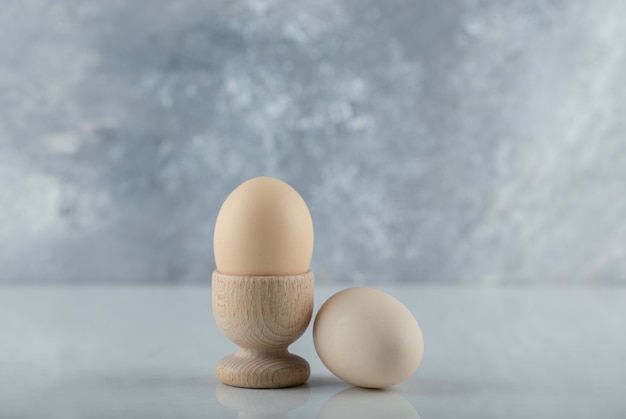 Free photo two fresh eggs in eggcup and ground on white background.