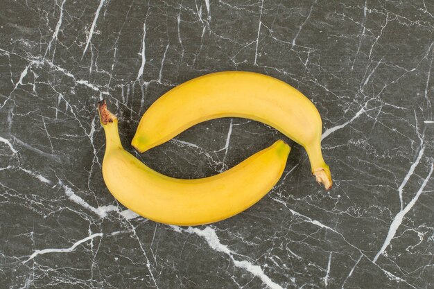 Two fresh organic banana on black stone