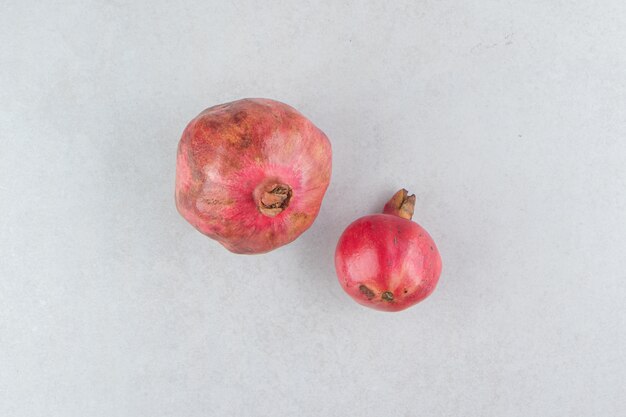 Two fresh pomegranates on stone table.