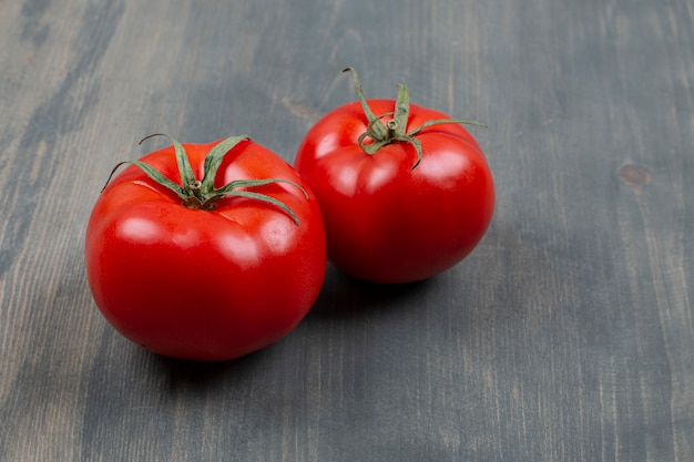 Two fresh raw tomatoes with leaves on a wooden table