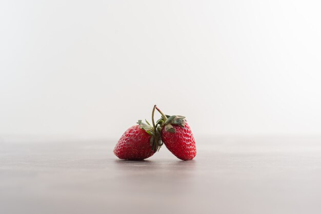 Two fresh strawberries on marble table.