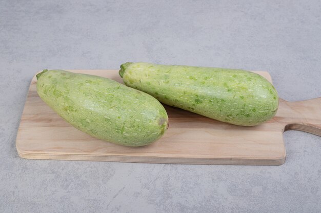 Two fresh zucchini on wooden board . High quality photo