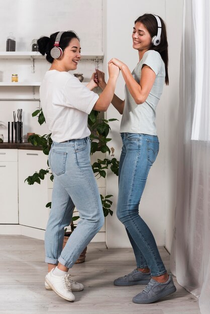 Two friends dancing at home with music on headphones