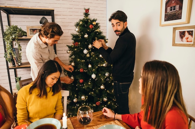 Two friends decorating tree at christmas dinner