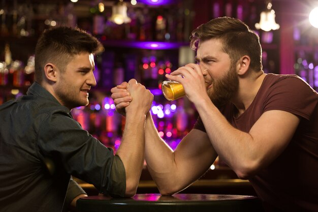 Two friends drinking beer and having fun at the pub