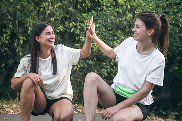 Free photo two friends highfive each other after jogging in the park