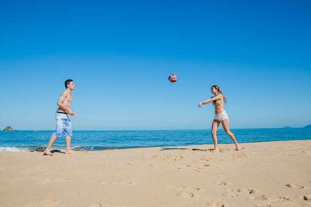 Free photo two friends playing beach volleyball