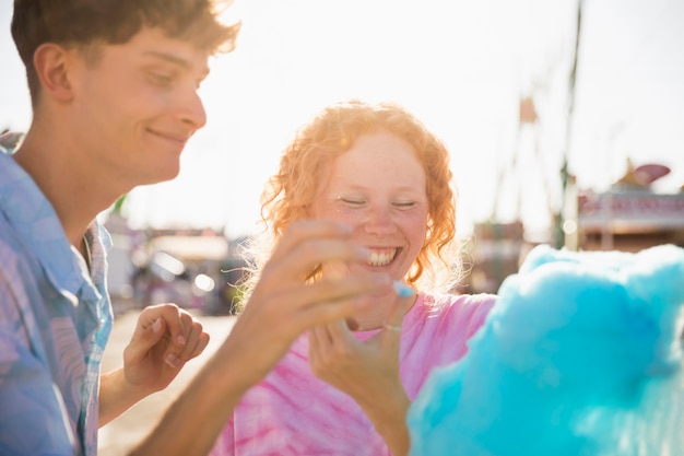 Two friends playing while eating cotton candy 