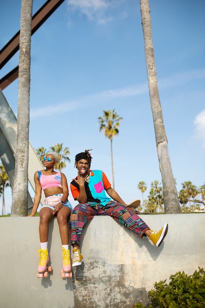 Two friends posing with roller skates and skateboard in the park