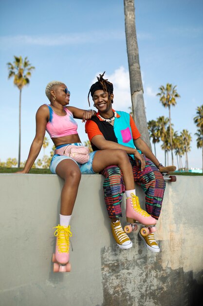 Two friends posing with their roller skates and skateboard outside in the park