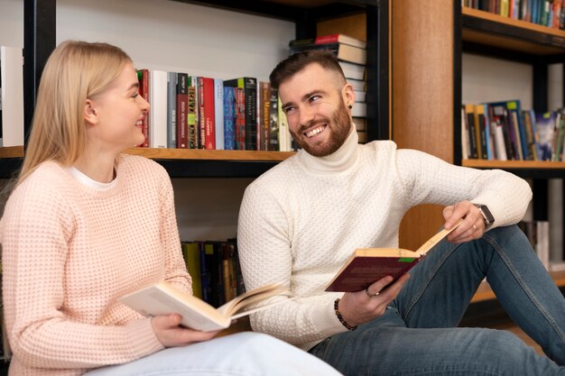 Two friends reading books in a library