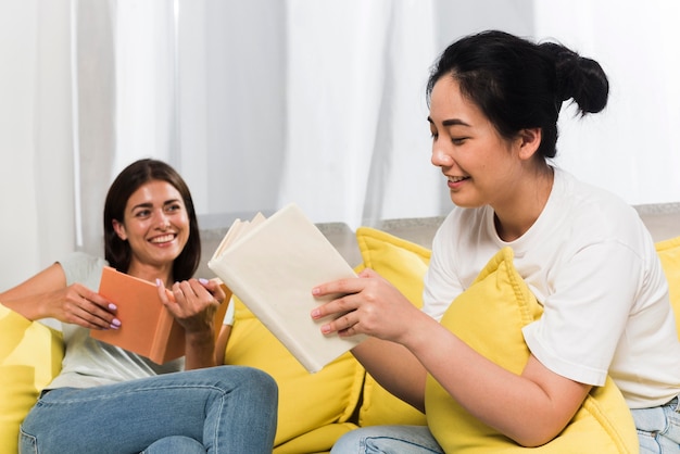 Two friends relaxing at home on couch with books