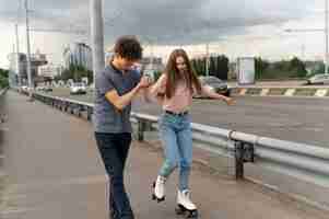 Free photo two friends spending time together outdoors using roller skates