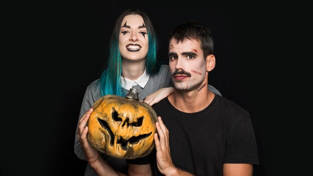 Two friends with spooky pumpkin on black background