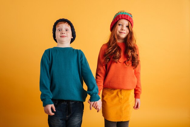 Two funny little children wearing warm hats