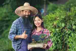 Free photo two gardeners smiling while holding pot of plant