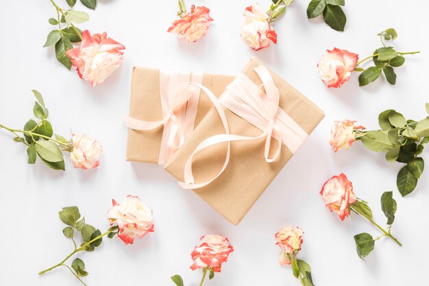 Две подарочные коробки, окруженные прекрасными розами на белом фоне