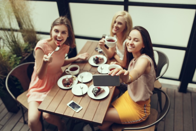 Free photo two girl friends spend time together drinking coffee in the cafe, having breakfast and dessert.