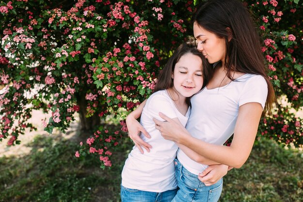 Two girl hugging standing under tree