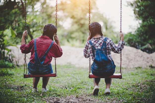 Two girl sitting on a swing together