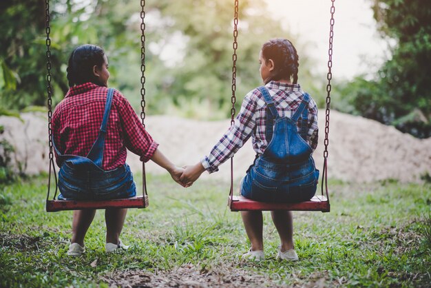 Two girl sitting on a swing together