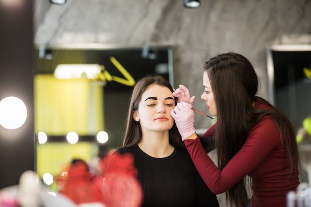 Two girls are doing make-up in front of big mirror