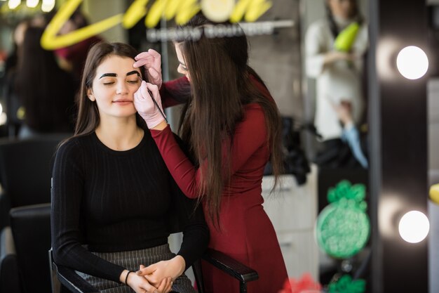 Две девушки делают макияж перед большим профессиональным зеркалом