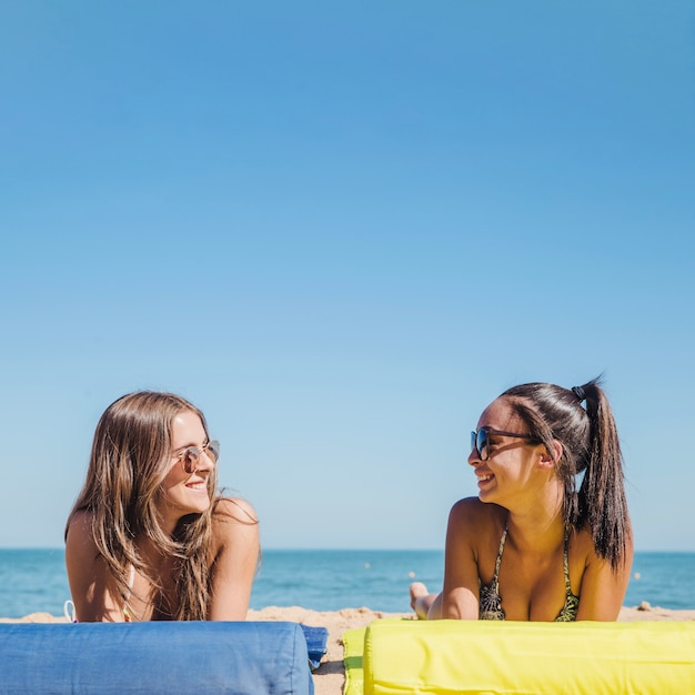 Two girls at the beach talking to each other