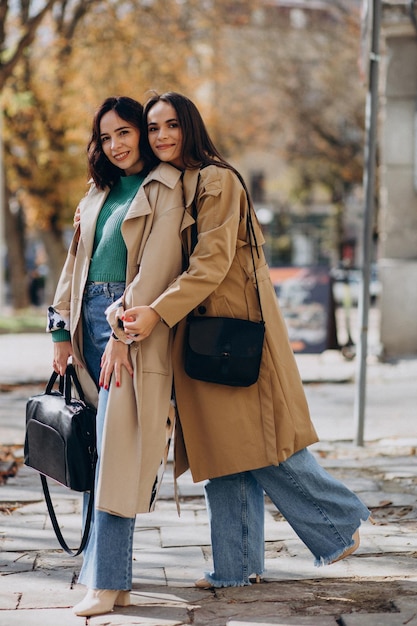 Two girls in coat walking together in the street