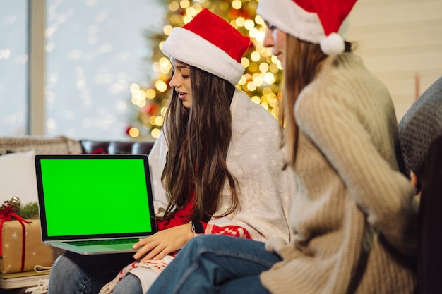 두 소녀는 인터넷을 통해 친구들과 소통합니다. 녹색 화면이 있는 노트북, 크로마키