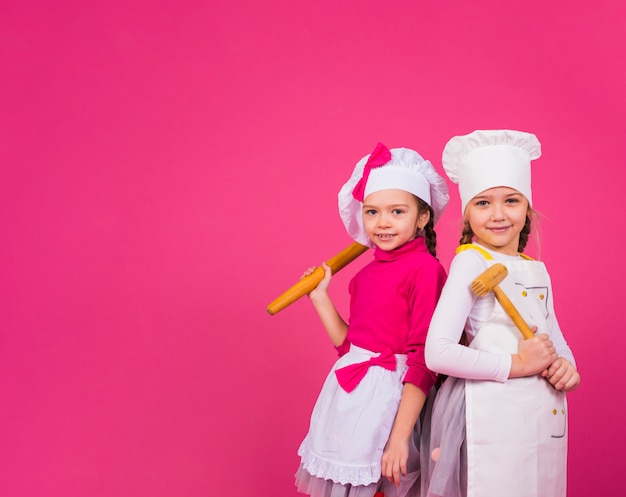 Foto gratuita due ragazze cuochi in piedi con utensili da cucina