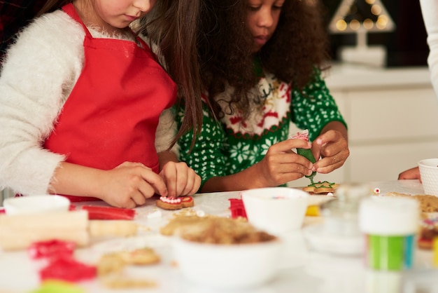 Foto gratuita due ragazze che decorano i biscotti di natale