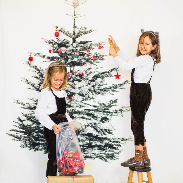 Two girls decorating christmas tree