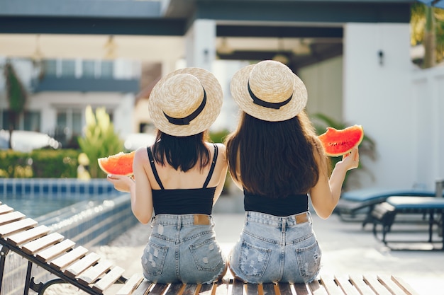 two girls eating watermelon by the pool in Thailand