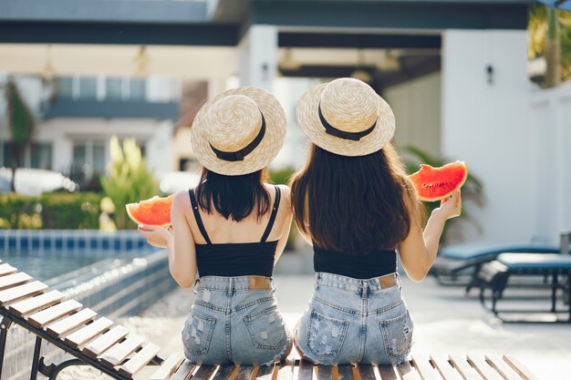 две девушки едят арбуз у бассейна в Таиланде