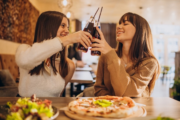 Two girls friends eating pizza in a cafe