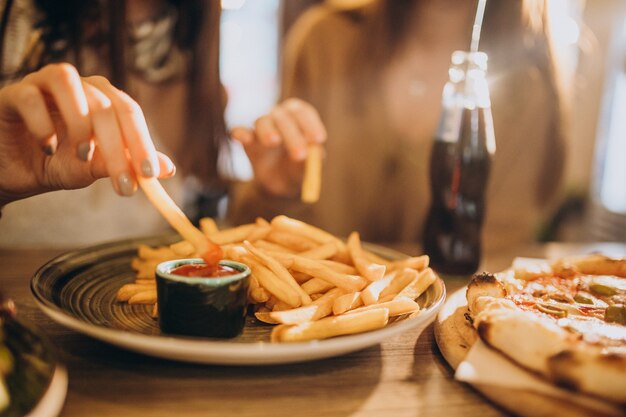 Two girls friends eating pizza in a cafe