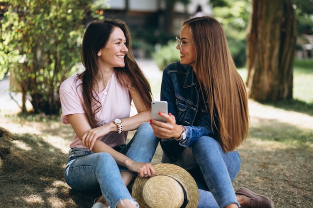 Due amici di ragazze che si siedono nel parco