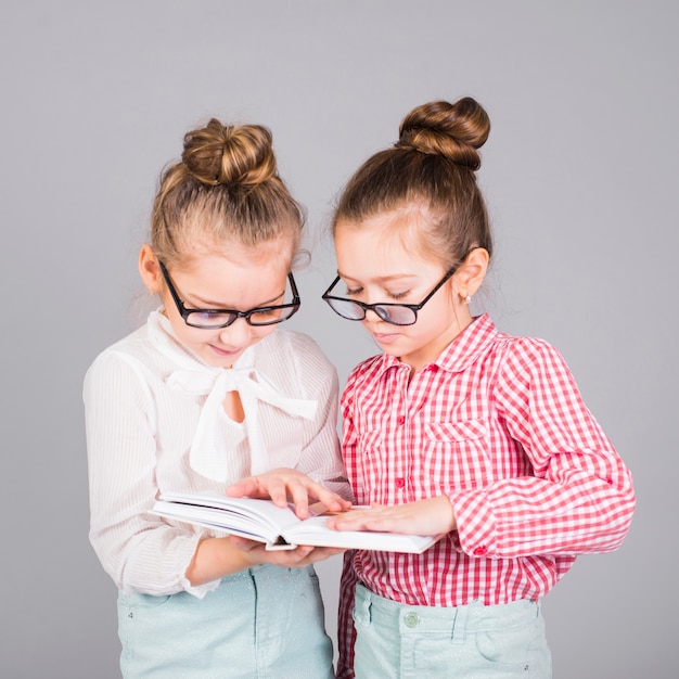 Two girls in glasses reading book