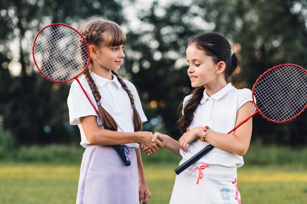 Two girls holding badminton shaking hands with each other