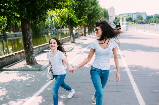 Two girls holding hands walking on pavement