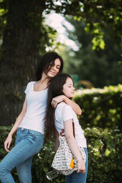 Two girls hugging relaxing standing outdoors