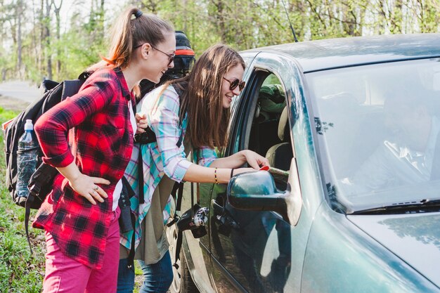 Two girls leaning towards car window