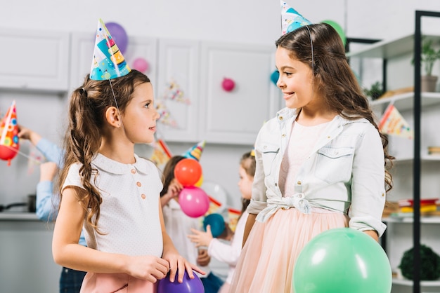 Two girls looking at each other while celebrating birthday in kitchen