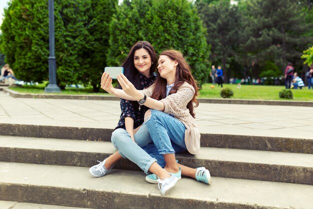 Two girls making funny selfie on the street, having fun together