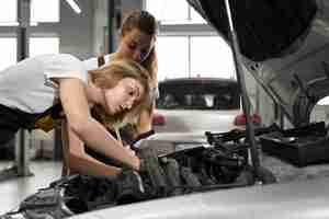 Free photo two girls mechanics and fixing automobile.