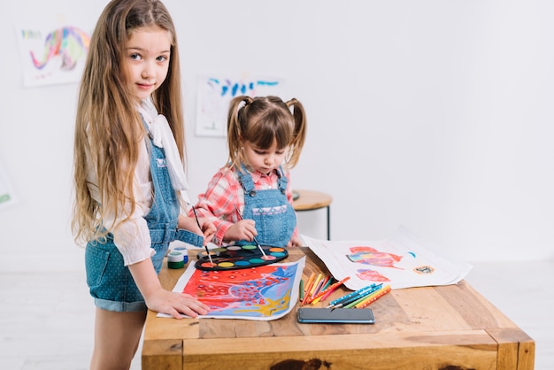Two girls painting with aquarelle on paper 