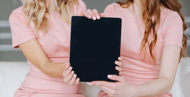 two girls in a pink dress together show of a tablet 