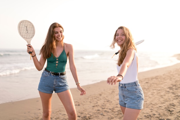 Two girls playing beach tennis near the seashore